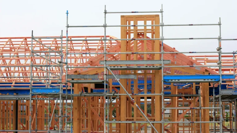 Wooden framed building being constructed with steel scaffolding